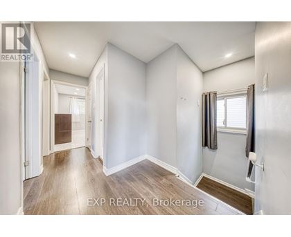A well-lit, empty room with a window and a door leading to another room.