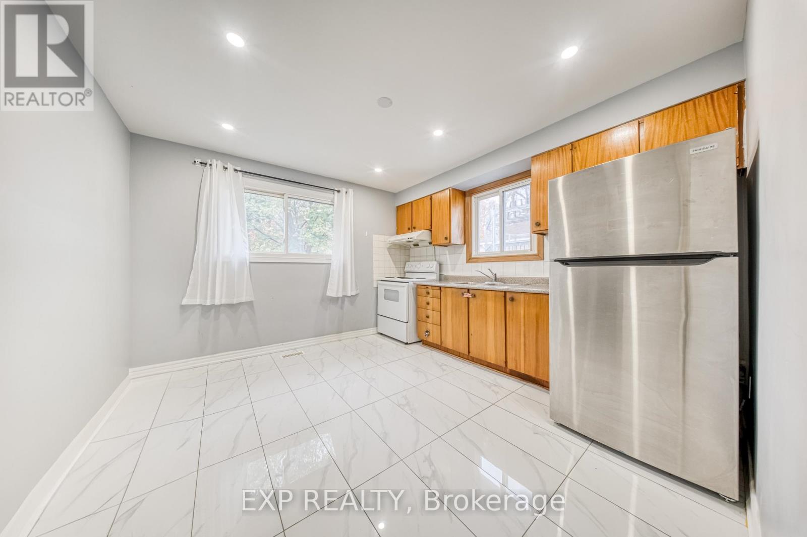 A kitchen with white tiled floors and wooden cabinets.