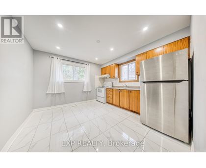 A kitchen with white tiled floors and wooden cabinets.