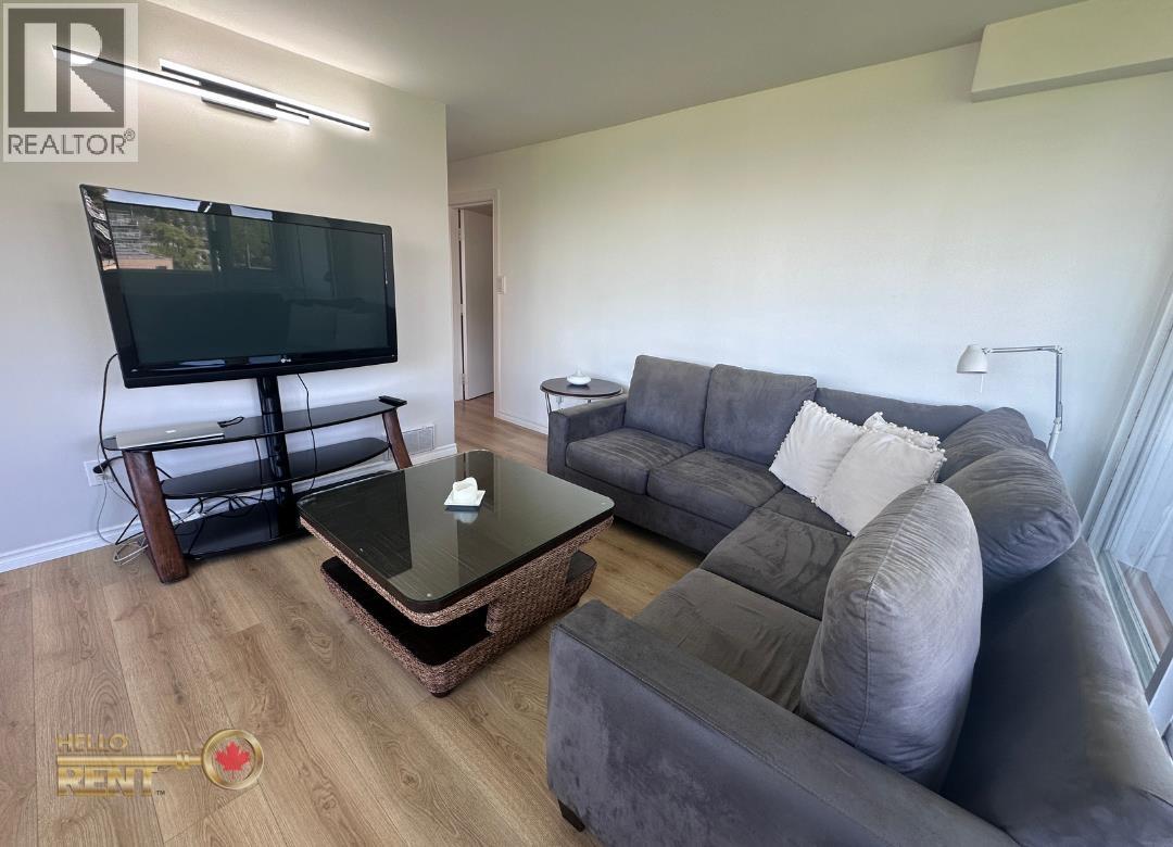 A living room with a grey couch, a coffee table, and a television.