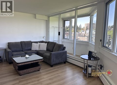 A living room with a grey couch and a glass table.
