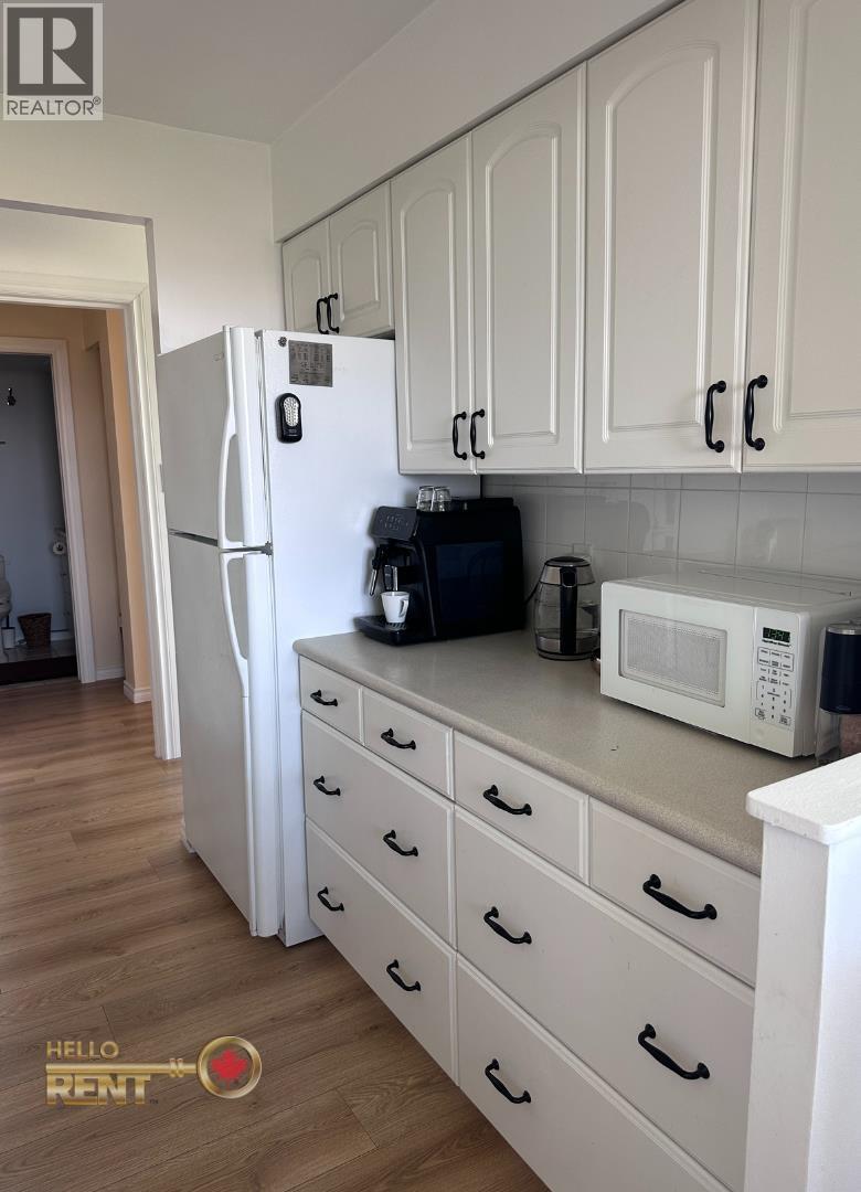 A kitchen with white cabinets and a white fridge.