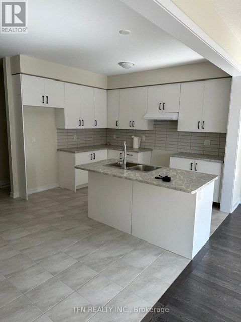 A kitchen with white cabinets and a marble countertop.