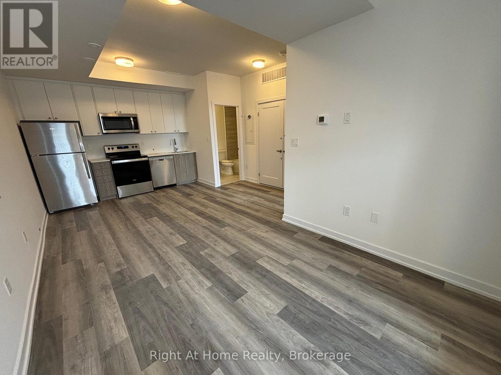 A kitchen with a refrigerator, oven, and microwave.