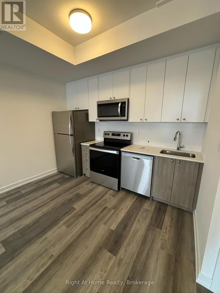 A kitchen with a refrigerator, microwave, oven, and sink.