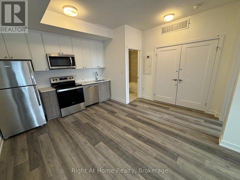 A kitchen with a refrigerator, microwave, and stove top oven.