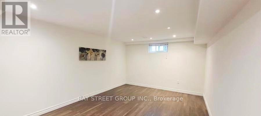 A spacious room with a wooden floor and a painting on the wall.