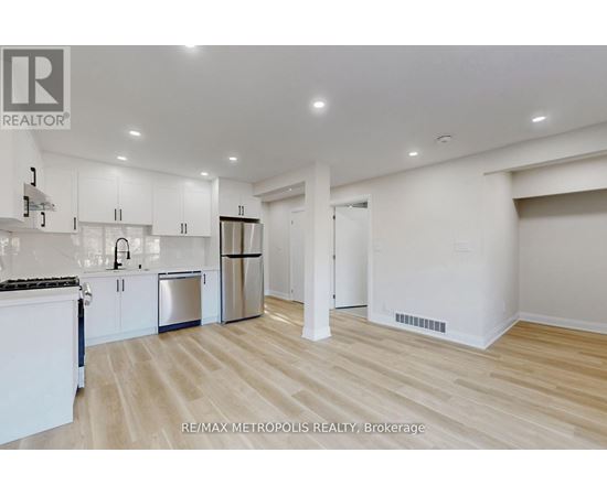 A spacious kitchen with white cabinets and a wooden floor.