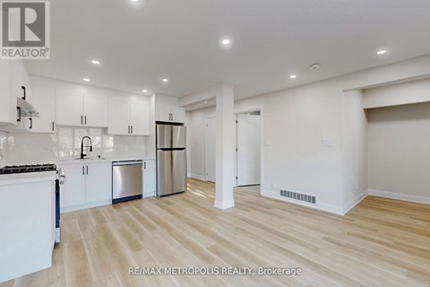 A spacious kitchen with white cabinets and a wooden floor.