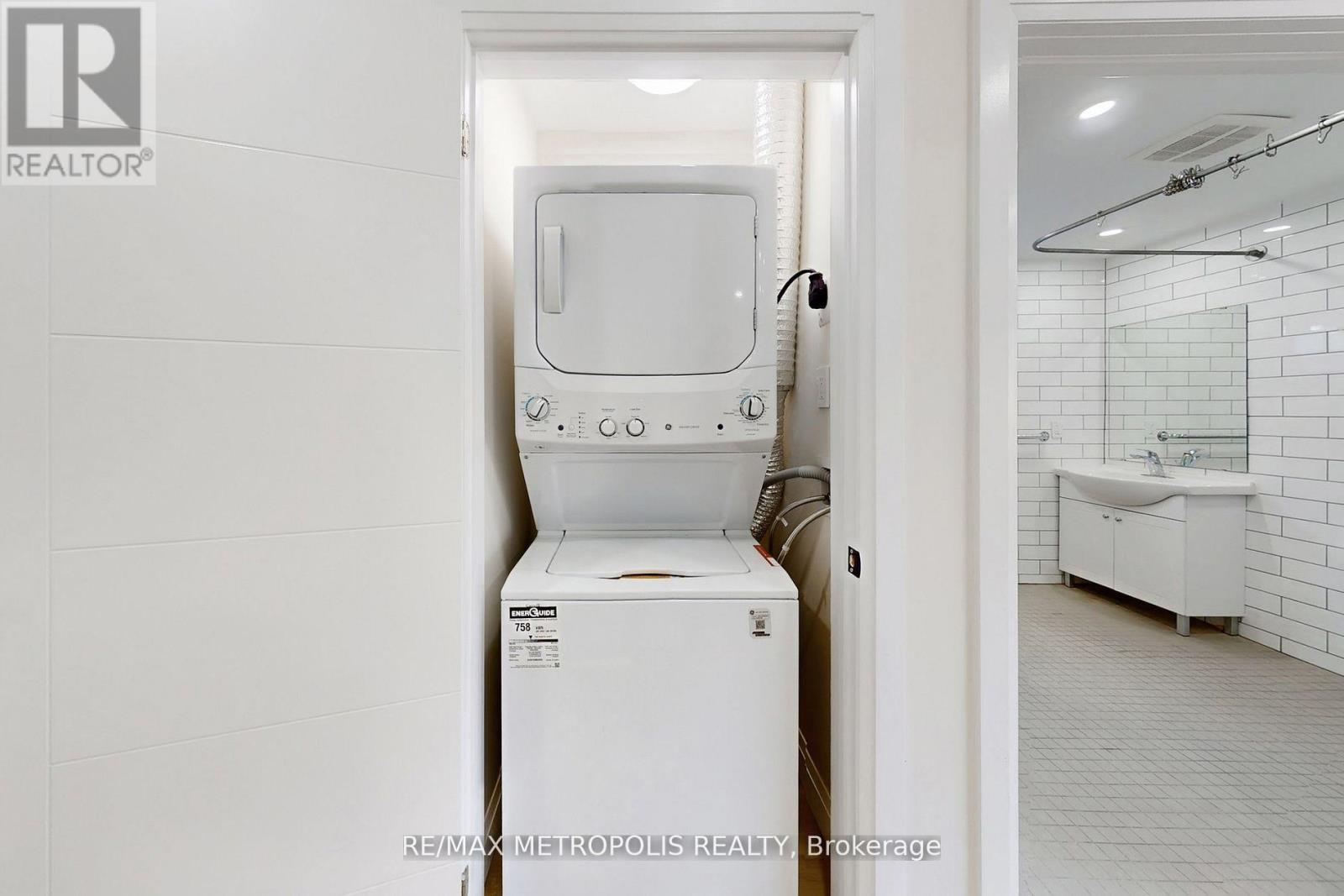 A white toilet is in a bathroom with a white tiled wall.