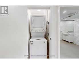 A white toilet is in a bathroom with a white tiled wall.