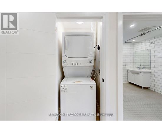 A white toilet is in a bathroom with a white tiled wall.