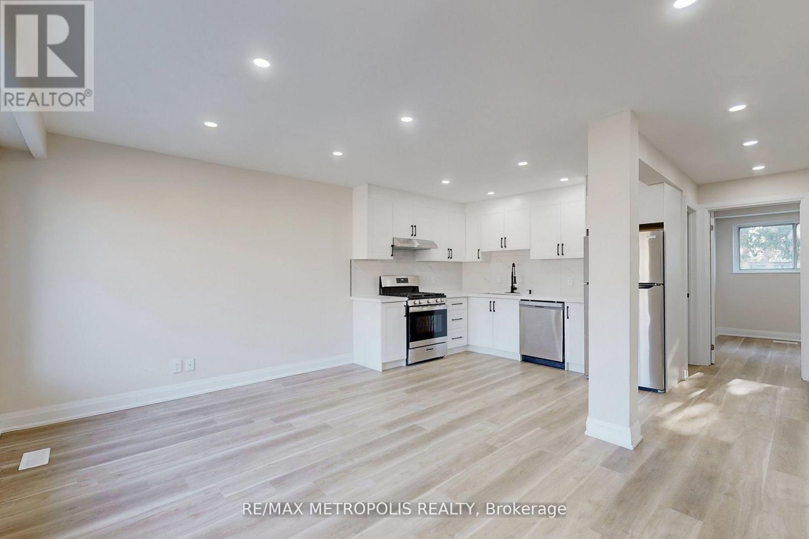 A spacious kitchen with white cabinets and a refrigerator.
