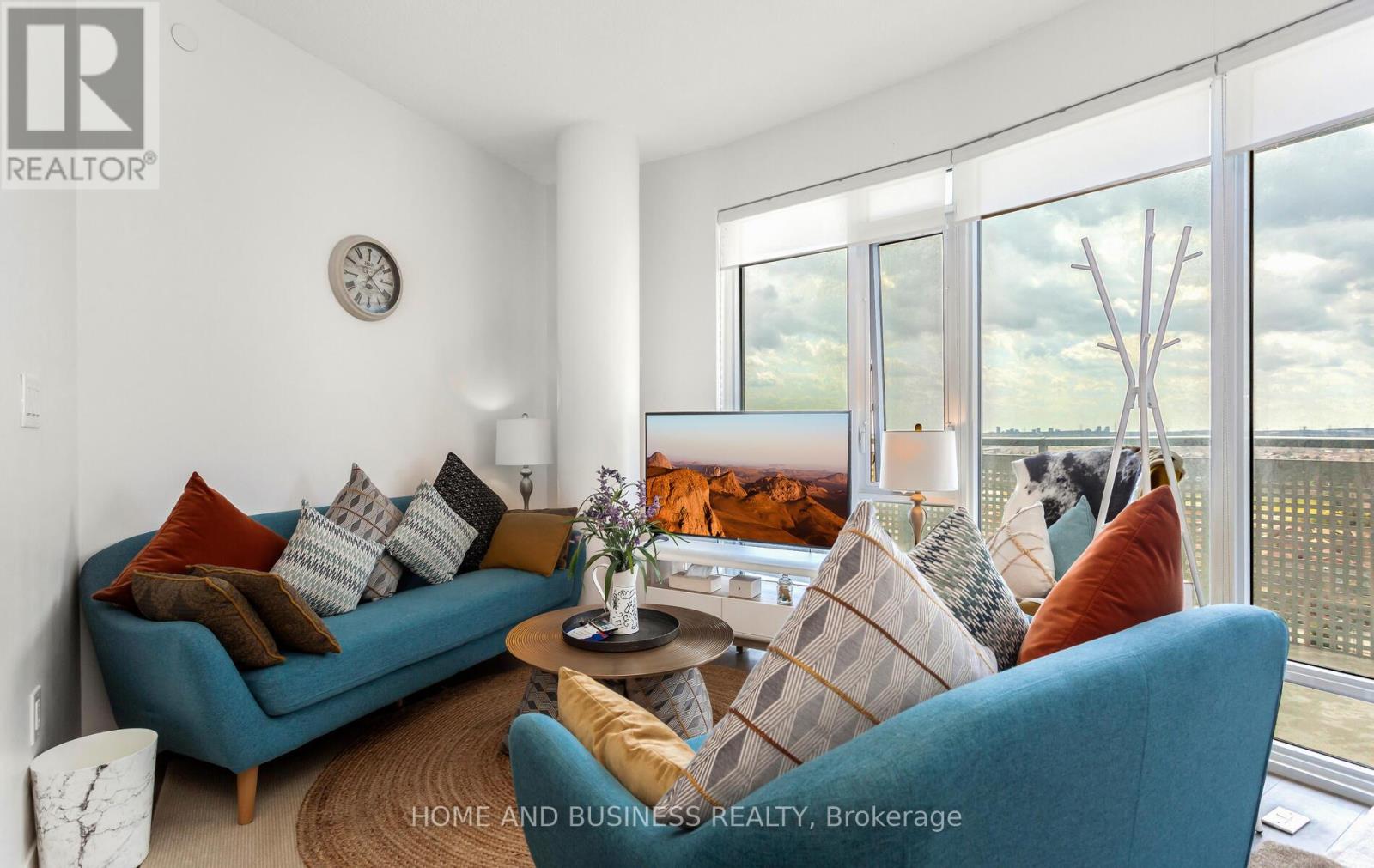 A living room with a blue couch and a clock on the wall.