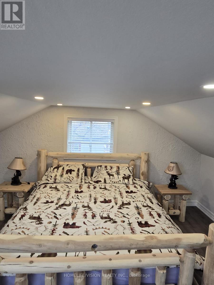 A bedroom with a bed, two lamps, and a window.