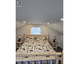 A bedroom with a bed, two lamps, and a window.