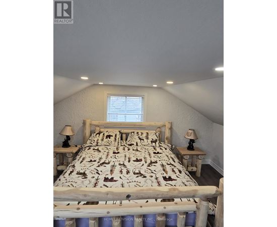 A bedroom with a bed, two lamps, and a window.
