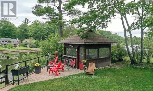 A gazebo with red chairs is surrounded by greenery.