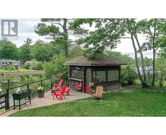 A gazebo with red chairs is surrounded by greenery.