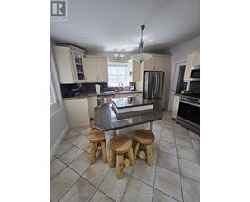 A kitchen with a granite countertop and wooden stools.