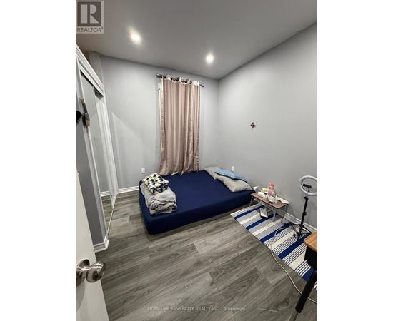 A bedroom with a bed, nightstand, and a striped rug.