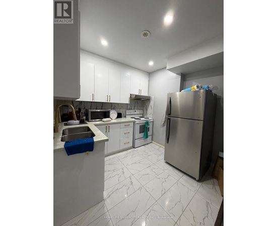 A kitchen with a refrigerator, sink, and cabinets.