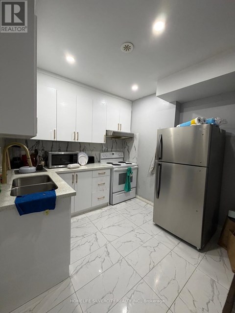 A kitchen with a refrigerator, sink, and cabinets.