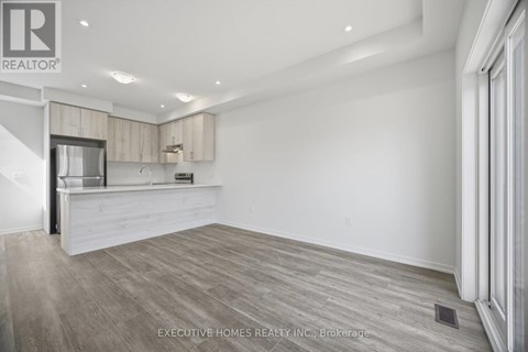 A spacious kitchen with white cabinets and a wooden floor.