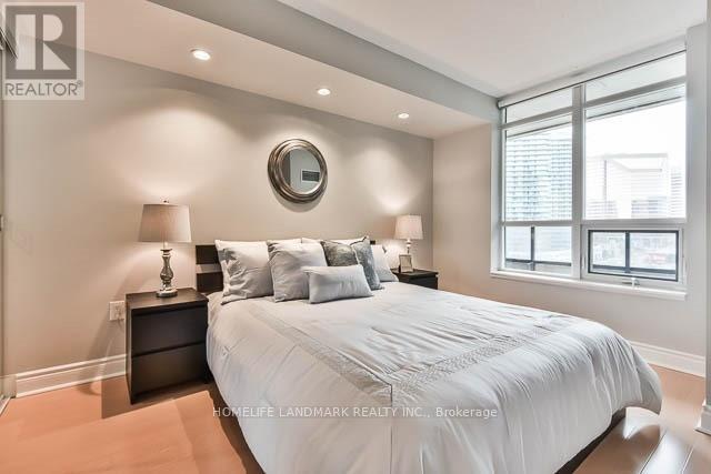 A bedroom with a large bed, two lamps, and a round mirror on the wall.
