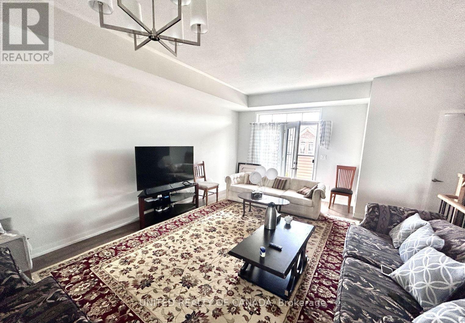 A living room with a rug on the floor and a television on the wall.