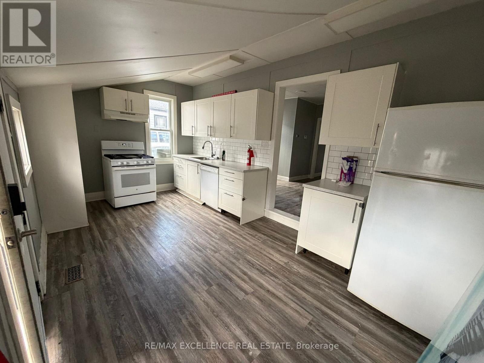 A kitchen with white cabinets and a wooden floor.
