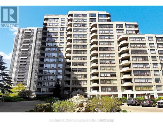 A large residential building with a parking lot in front.