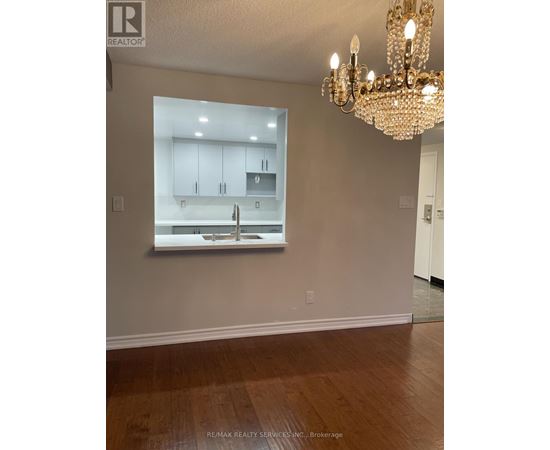 A chandelier hangs over a kitchen counter in a well-lit room.