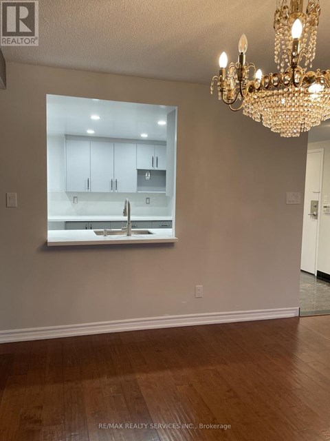 A chandelier hangs over a kitchen counter in a well-lit room.