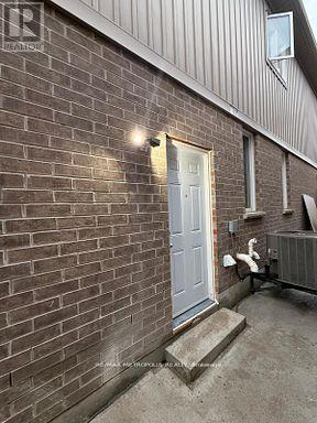 A white door is on the right side of a brick building.