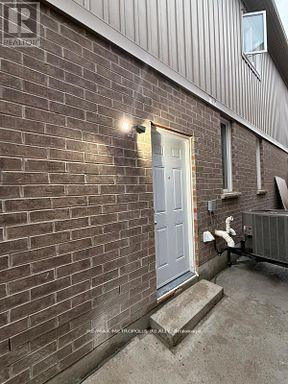 A white door is on the right side of a brick building.