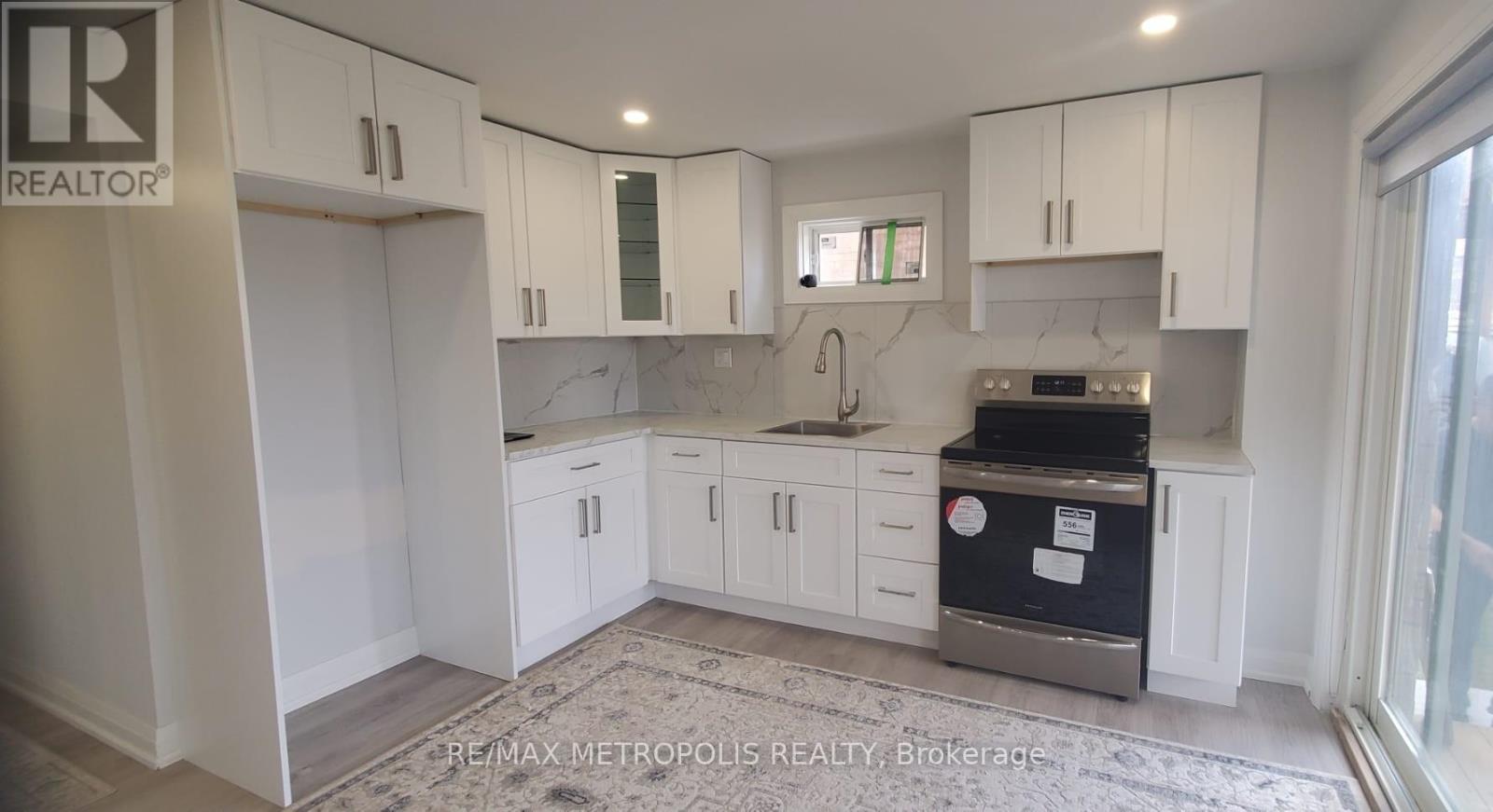 A kitchen with white cabinets and a black fridge.