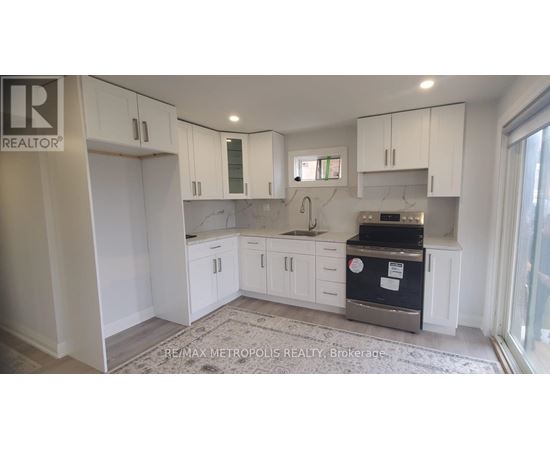 A kitchen with white cabinets and a black fridge.