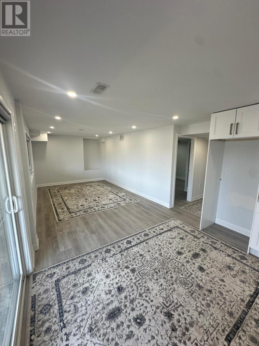 A large, empty room with a rug on the floor and a door to the right.