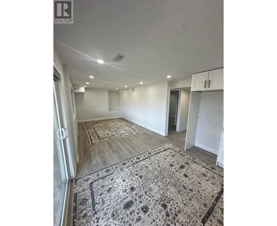 A large, empty room with a rug on the floor and a door to the right.
