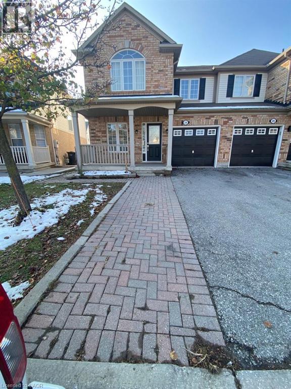 A brick walkway leads to a house with a black garage door.