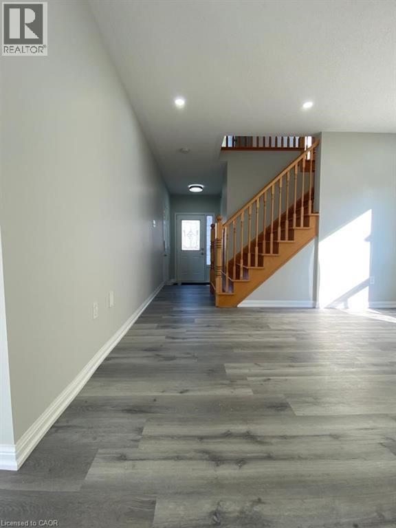 A long hallway with a wooden staircase.