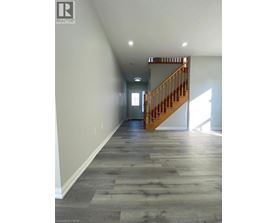 A long hallway with a wooden staircase.