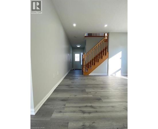 A long hallway with a wooden staircase.