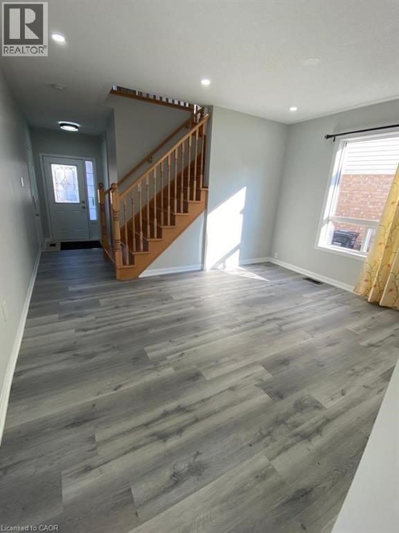 A spacious room with a wooden staircase and grey flooring.