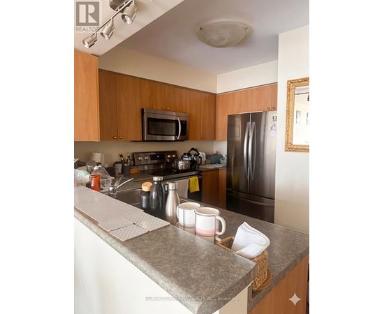 A kitchen with a refrigerator, microwave, and oven.