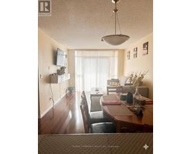 A dining room with a table set for two and a television mounted on the wall.
