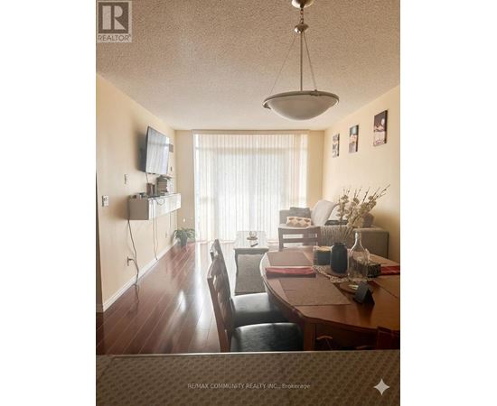 A dining room with a table set for two and a television mounted on the wall.