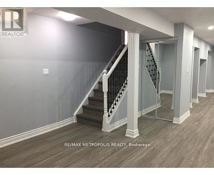 A hallway with a staircase and a brokerage sign.