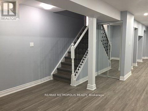 A hallway with a staircase and a brokerage sign.